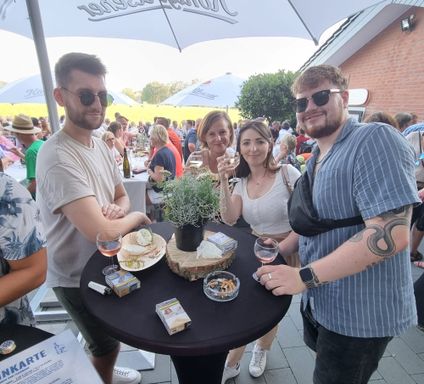 Lächelnde Menschen mit Weingläsern an einem Stehtisch