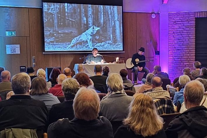 Menschen sitzen im Ratssaal und hören einem Vortrag zu