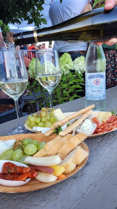 Zwei Teller mit Weintrauben und Brot, dahinter zwei Weingläser
